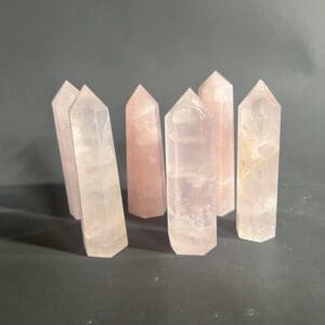 A group of five pink quartz points on top of a table.