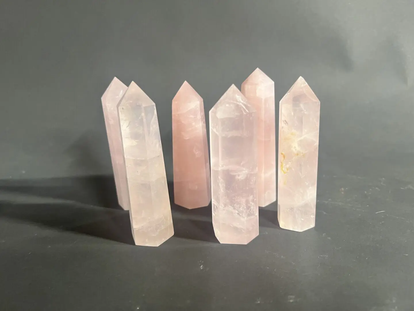 A group of five pink quartz points on top of a table.