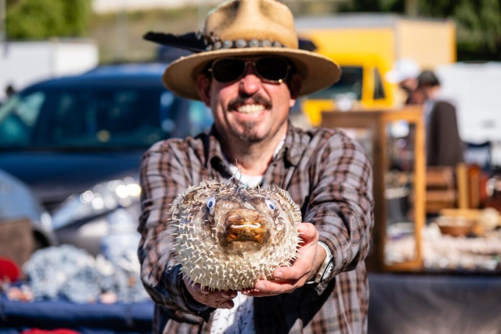 A man holding a Puffer Fish at a flea market.