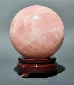 A pink crystal ball sitting on top of a wooden stand.