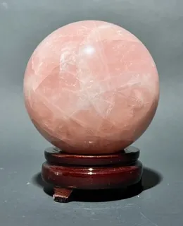 A pink crystal ball sitting on top of a wooden stand.