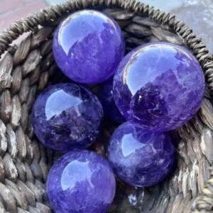 A basket of purple balls sitting on top of the ground.