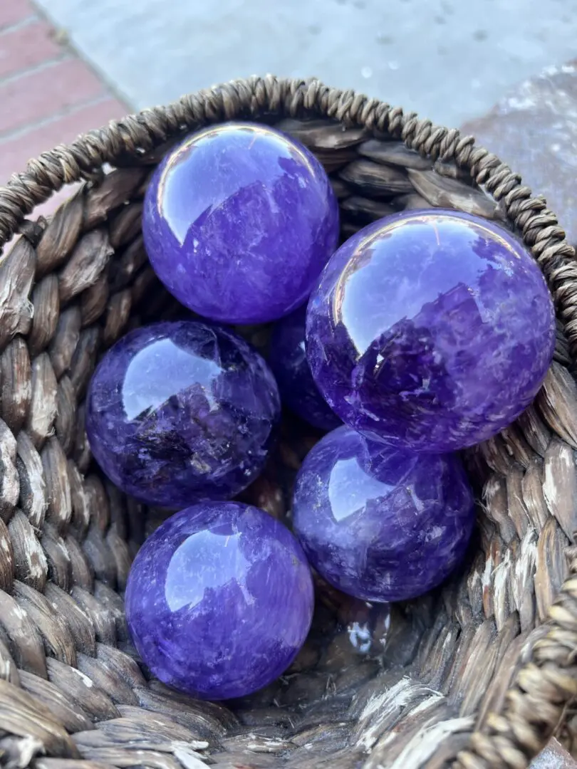 A basket of purple balls sitting on top of the ground.