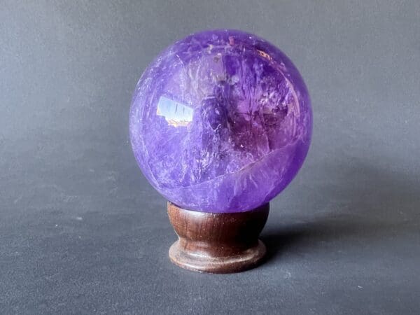 A purple crystal ball sitting on top of a wooden stand.