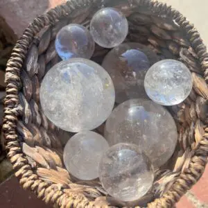 Sentence with the product name: Clear quartz spheres in a clear wicker basket.