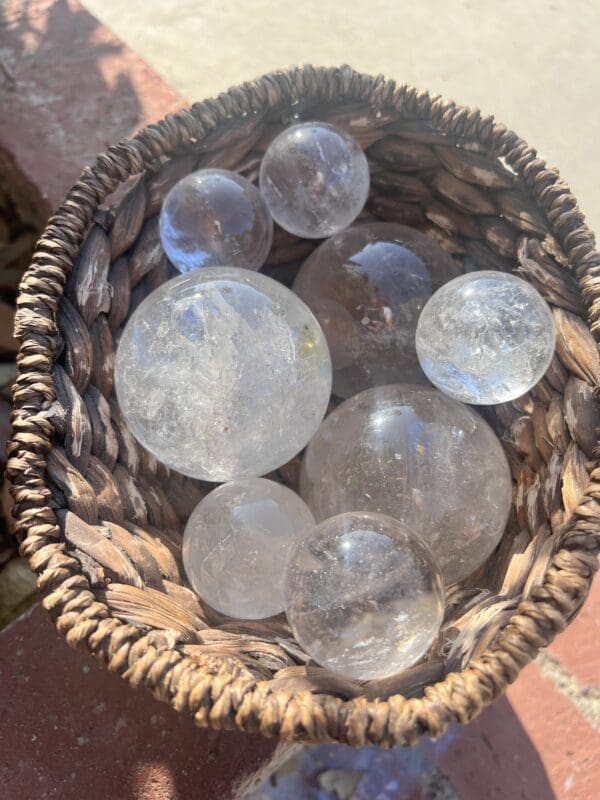 Sentence with the product name: Clear quartz spheres in a clear wicker basket.