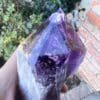 A person holding a Large Amethyst Dragon's Tooth Scepter From Bahia, Brazil 724 grams crystal.