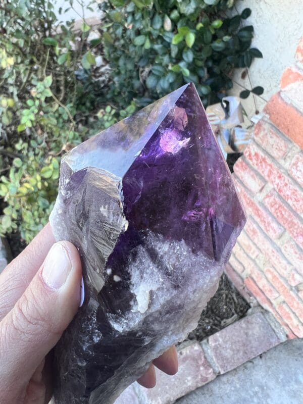 A person holding up a Large Amethyst Dragon's Tooth Scepter From Bahia, Brazil 724 grams.