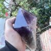 A person holding a large Amethyst Dragon’s Tooth Scepter from Bahia, Brazil 840 grams.