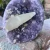 A piece of Uruguayan Amethyst Cut Base with Secondary Calcite 1,212 grams sitting on top of a rock.