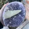 A person holding a piece of Uruguayan Amethyst Cut Base with Secondary Calcite 1,212 grams in their hand.