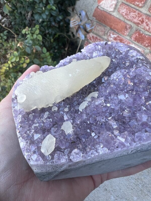 A person is holding a piece of Uruguayan Amethyst Cut Base with Secondary Calcite 1,212 grams crystal.