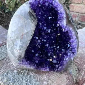 An Uruguayan Amethyst Cut Base with Secondary Calcite 932 grams shaped rock sitting on top of a rock.