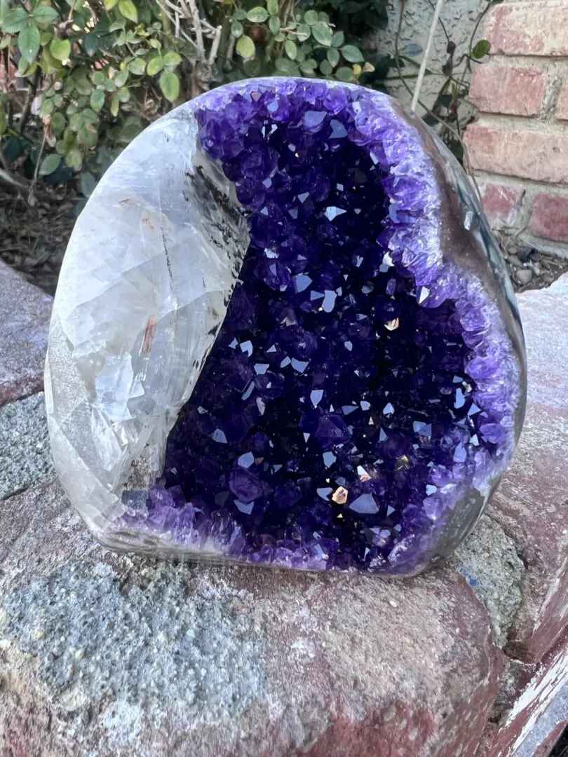 An Uruguayan Amethyst Cut Base with Secondary Calcite 932 grams shaped rock sitting on top of a rock.