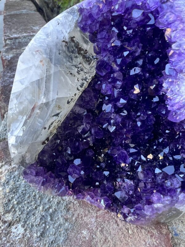 Uruguayan Amethyst Cut Base with Secondary Calcite 932 grams in a bag on the ground.