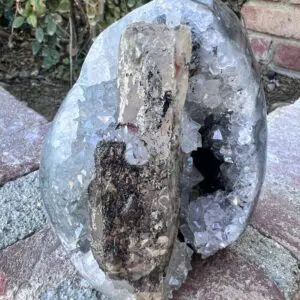 A rock with a piece of Uruguayan Clear Quartz Cut Base Geode with Secondary Calcite sitting on top of it.