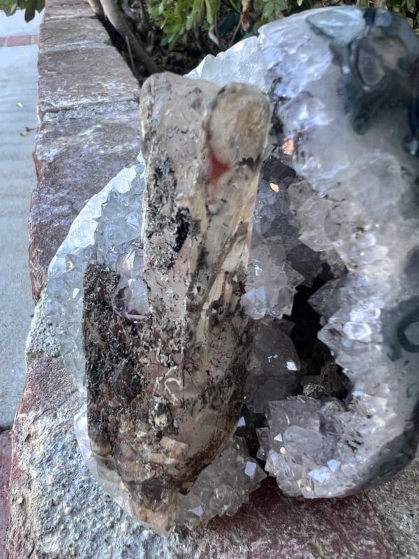 A piece of Uruguayan clear quartz cut base geode with secondary calcite sitting on a rock.