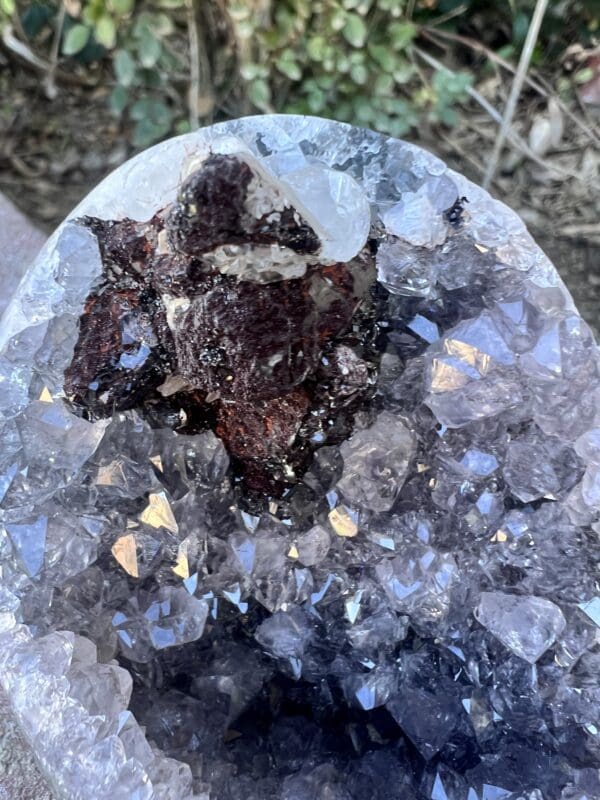 A Uruguayan Amethyst Cut Base with Secondary Calcite 412 grams sitting on top of a rock.