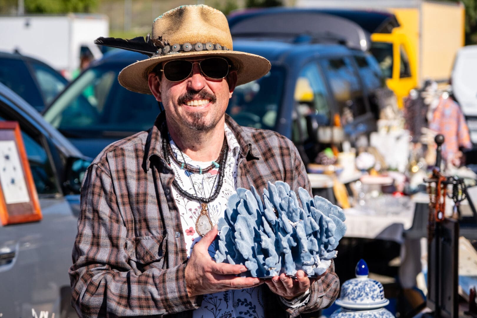 A man in a hat holding a blue rock.