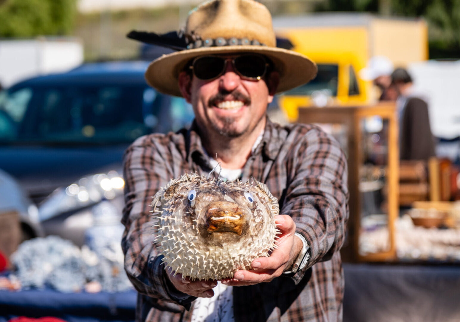 A man holding a Puffer Fish at a flea market.